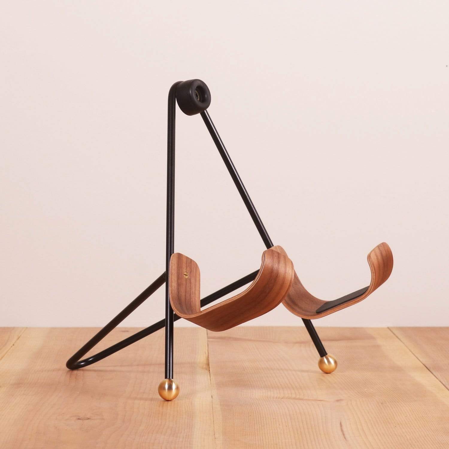 A Black guitar stand with wooden guitar body rests 