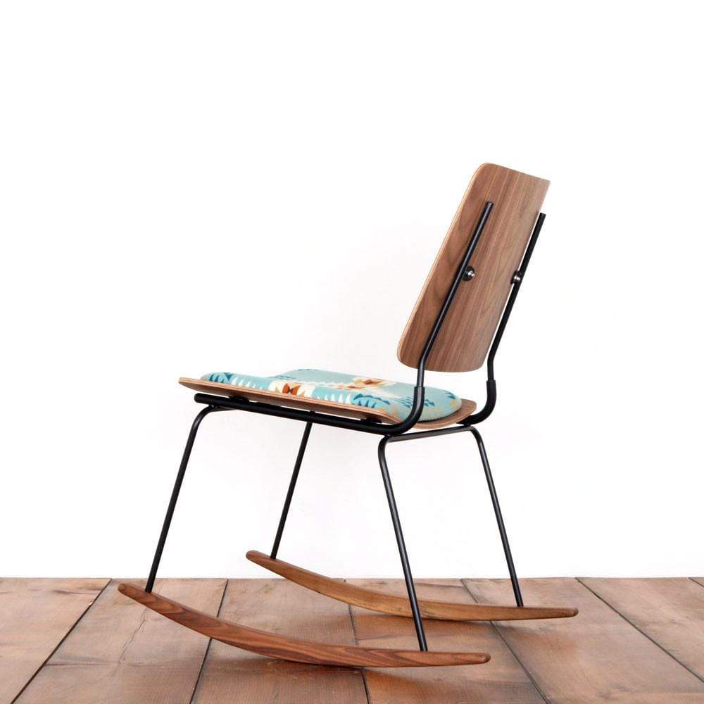 The back of a molded plywood rocking chair with no arms and a Pendleton seat cushion