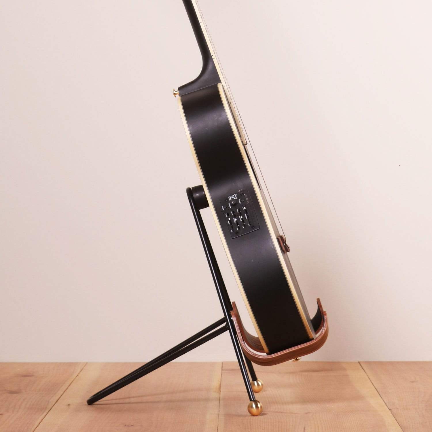 A sideview of a black acoustic guitar sitting inside of a guitar stand